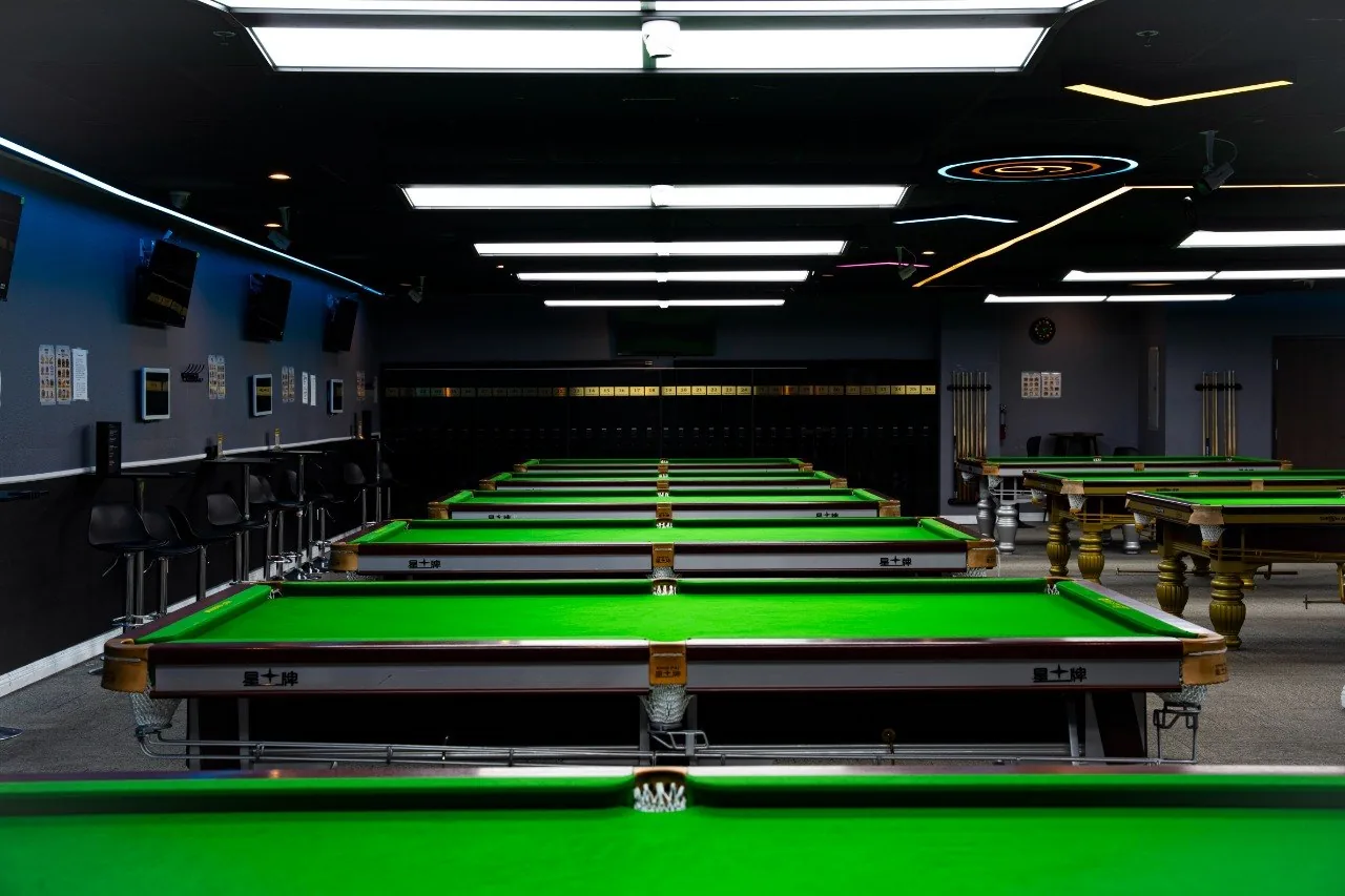Rows of professional billiard tables and focused lighting inside iCUE Billiard Club